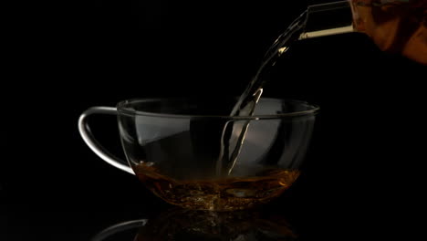 tea pouring from teapot in glass cup