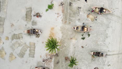 aerial view of fisherman repairing fish nets besides traditional wooden boats on kuakata sea beach, bangladesh