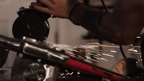 close shot of tattoos on the arm of a mechanic grinding metal with metal disk in fabrication workshop