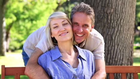 happy man hugging his partner on park bench