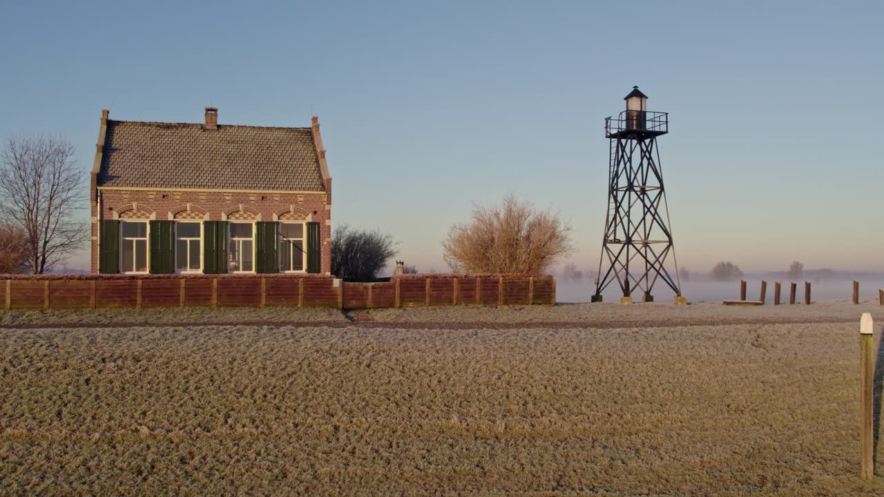 Ripresa aerea di un faro storico e una casa circondati da prati tranquilli, Schokland