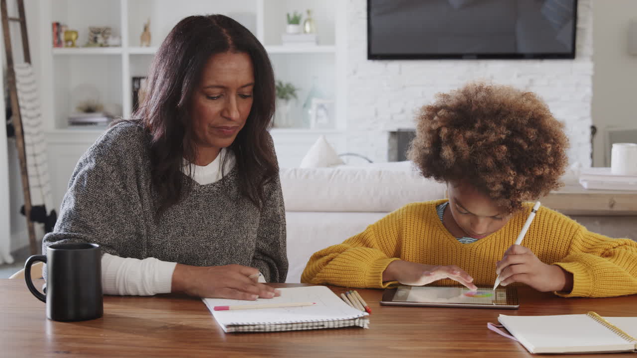 Middle aged woman sitting at the dining room table working with her granddaughter, panning shot
