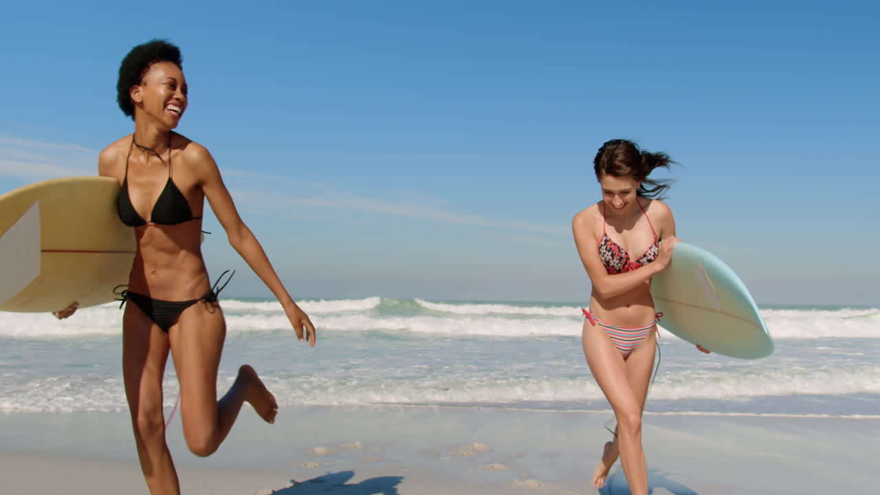 молодые подруги бегут с доской для серфинга.