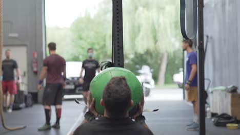 hombre irreconocible haciendo ejercicios con una pelota de medicina