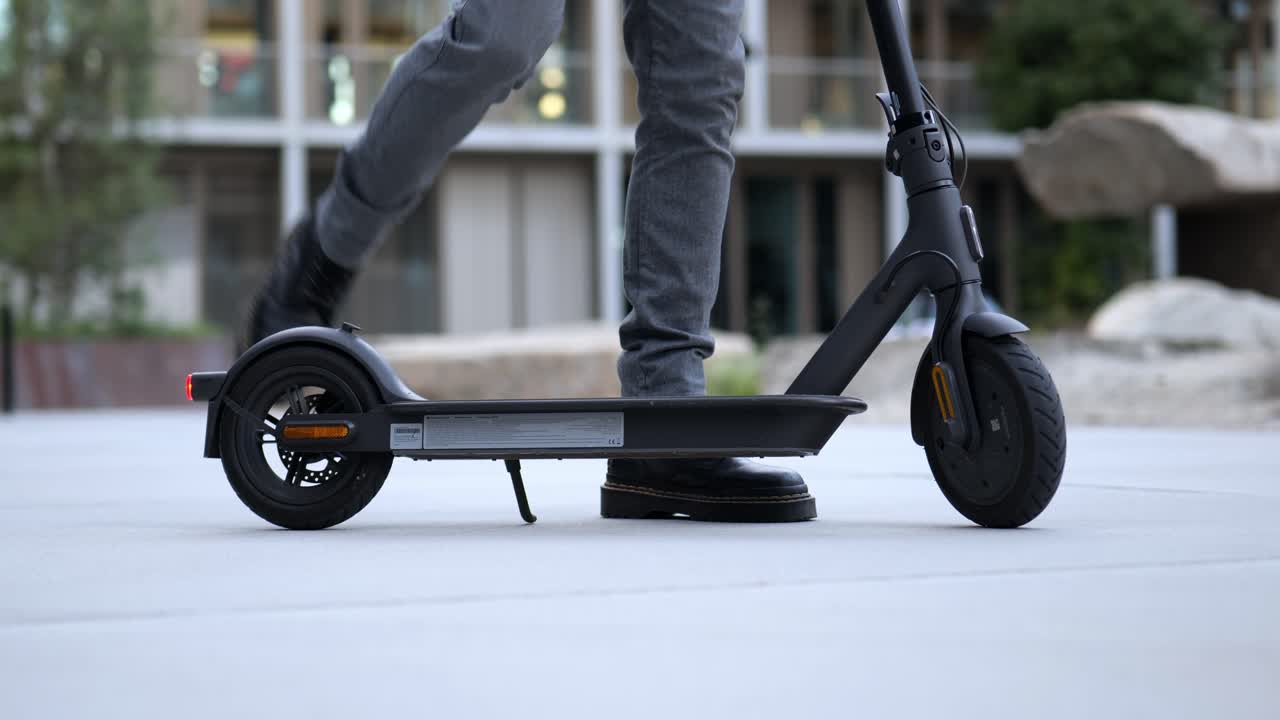 Close up of a businessman getting on an e-scooter and driving away