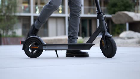 close up of a businessman getting on an e-scooter and driving away