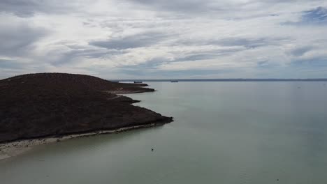 Ascending-aerial-view-of-a-beautiful-coastline-overlooking-the-dry-landscape-of-Playa-El-Tecolote-in-Baja-California-Sur,-Mexico-during-a-great-trip