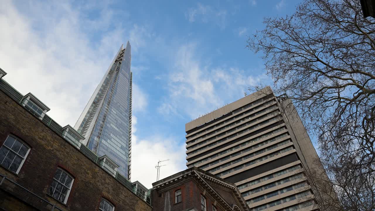 Low-angle perspective looking up at the glass Shard skyscraper and the brutalist Tower Wing of Guy's Hospital in the Southwark area of London