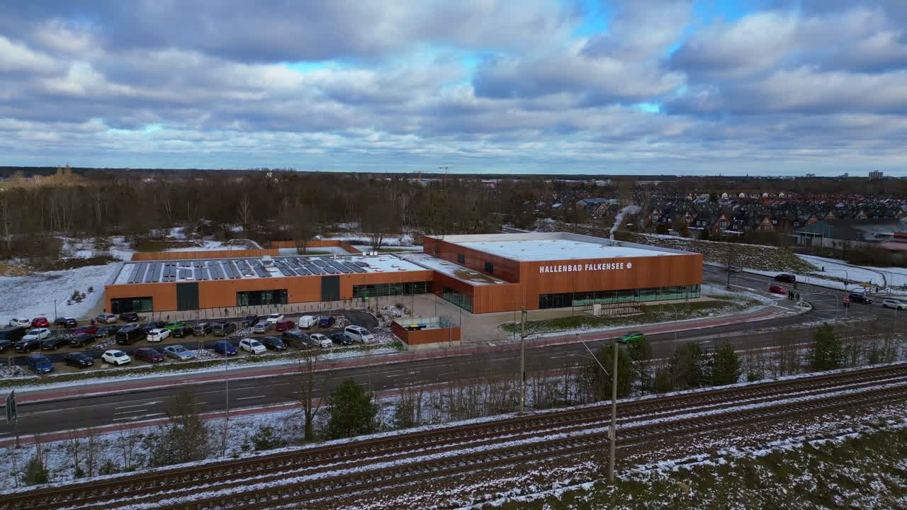 Indoor swimming pool with solar panels surrounded by snow and suburban homes in Falkensee Germany. Fantastic aerial view flight panorama overview drone