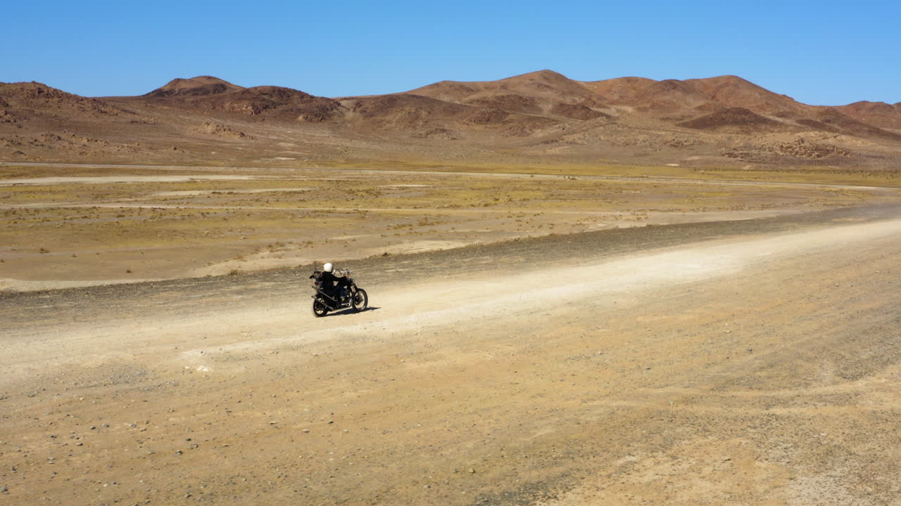 Viaggio in moto nel deserto durante una giornata calda, soleggiata e limpida.