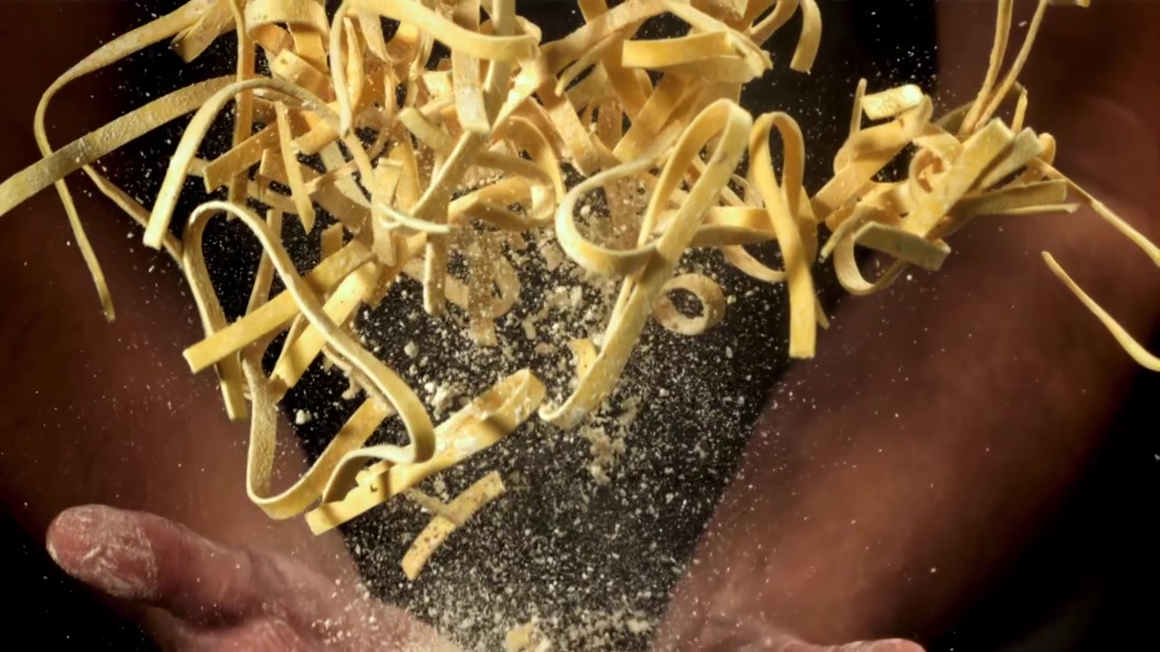Pasta fresca e farina che cadono dalle mani al rallentatore