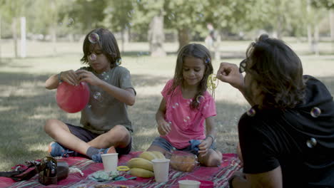 family having picnic in public park on summer day