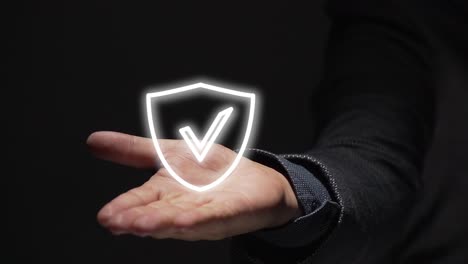 business man hand shows a shield with a check mark icon on black background