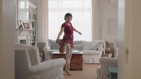 happy teenage girl dancing practicing ballet dance moves at home listening to music wearing headphones having fun enjoying weekend