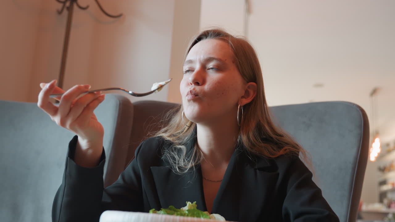 Donna che assapora un'insalata in un caffè, content creator che gusta verdure fresche con un sorriso gioioso, primo piano del movimento della forchetta, accogliente angolo di bistrò, luce naturale calda, scena di pranzo informale, atmosfera da foodie di tendenza