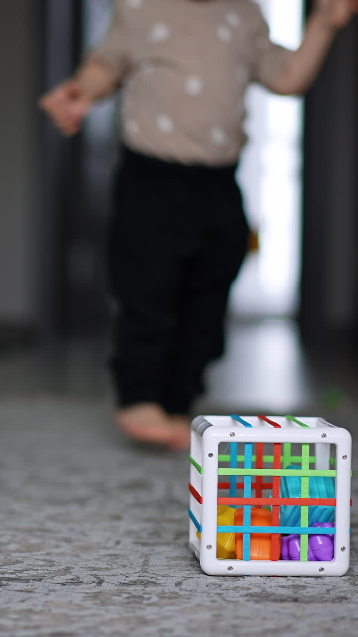 Little boy runs along the room approaching camera. Child goes past toys lying on the floor. Vertical video