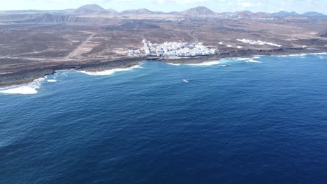 Droneshot-Ot-El-Hermoso-Pueblo-De-La-Santa-En-Lanzarotes-Wild-North-Coart,-Pequeñas-Casas-Blancas-Y-Volcanes-En-El-Fondo