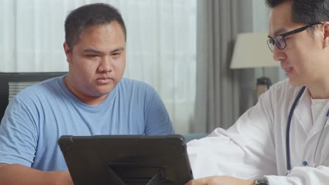 close up of asian male doctor with a fat male patient in clinic, sitting at desk and discussing about the results of medical check up on a tablet