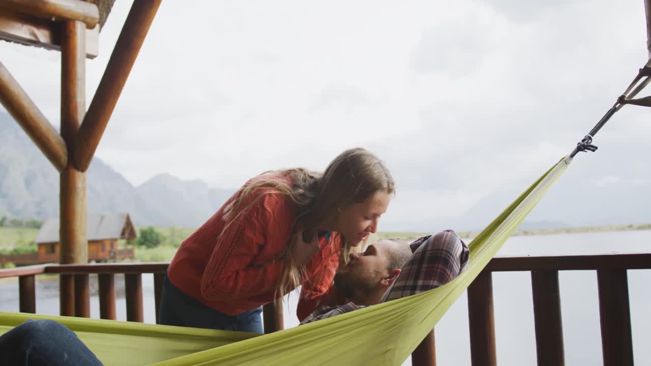 una pareja caucásica pasando tiempo en casa, besándose fuera de la cabaña.