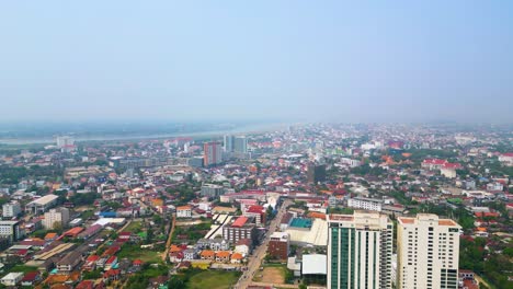 Rise-up-aerial-shot-of-Vientiane-cityscape-the-capital-of-Laos,-revealing-vibrant-rooftops-adorned-over-the-residential-area