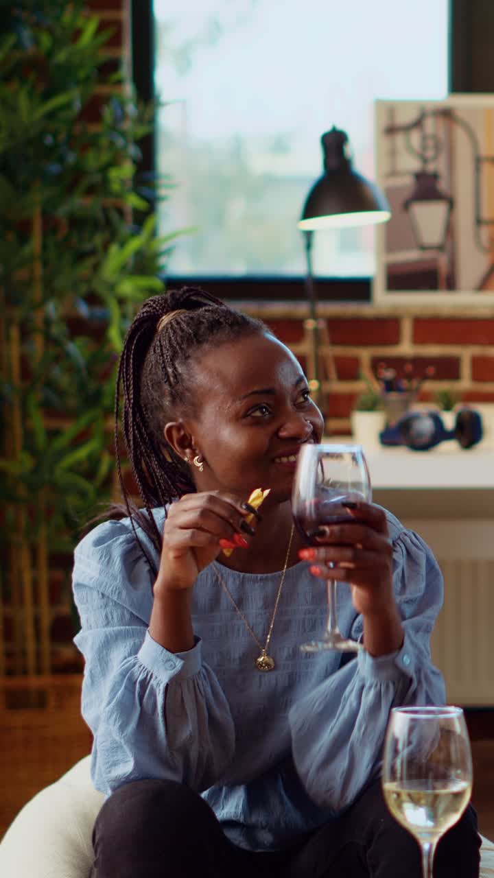Vertical video Guest making multiethnic group of people laugh in living room while drinking alcoholic beverages