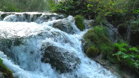 Cascading-water-along-a-series-of-large-moss-covered-rocks-in-Plitvice-Lakes-National-Park-in-Croatia,-Europe-at-¼-speed