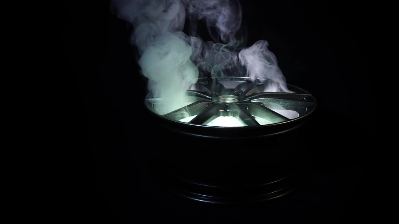 현대적인 아름다운 자동차 합금 바는 빛의 광선과 반임, 검은 배경, 연기가 강조하는 광선의 형태입니다.