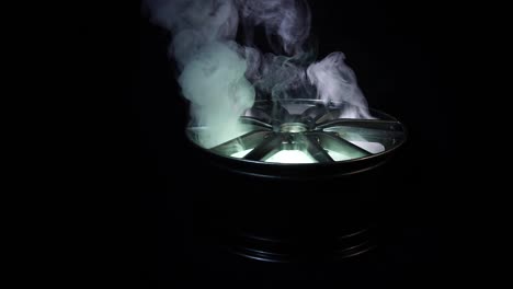 modern beautiful car alloy wheel in the form of rays that is highlighted by rays of light and sparkle, black background, smoke