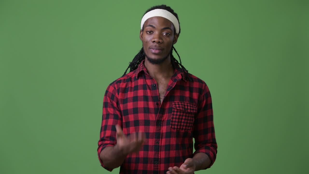 Giovane e affascinante uomo africano con i dreadlock su sfondo verde