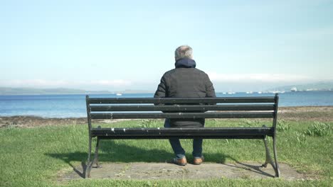 a man in his fifties takes a seat by the seaside and looks out to sea remembering his past and looking to his future