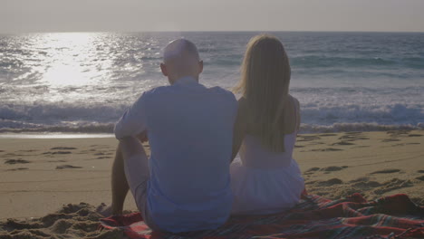 una pareja enamorada mirando el atardecer en la orilla del mar