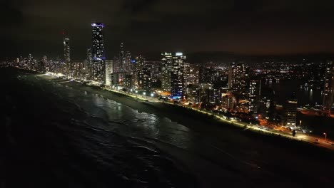 Absolut-Atemberaubende-Ausblicke,-Drohnen,-Die-Hoch-über-Dem-Meer-Fliegen-Und-Die-Nachtlandschaft-Des-Surferparadieses-Mit-Glitzerndem-Wasser-Und-Funkelnden-Hochhauslichtern-Einfangen