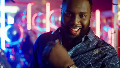 affectionate man winking in club. guy calling somebody with gesture at party