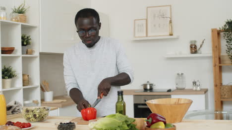 african american man preparing vegetable salad in kitchen