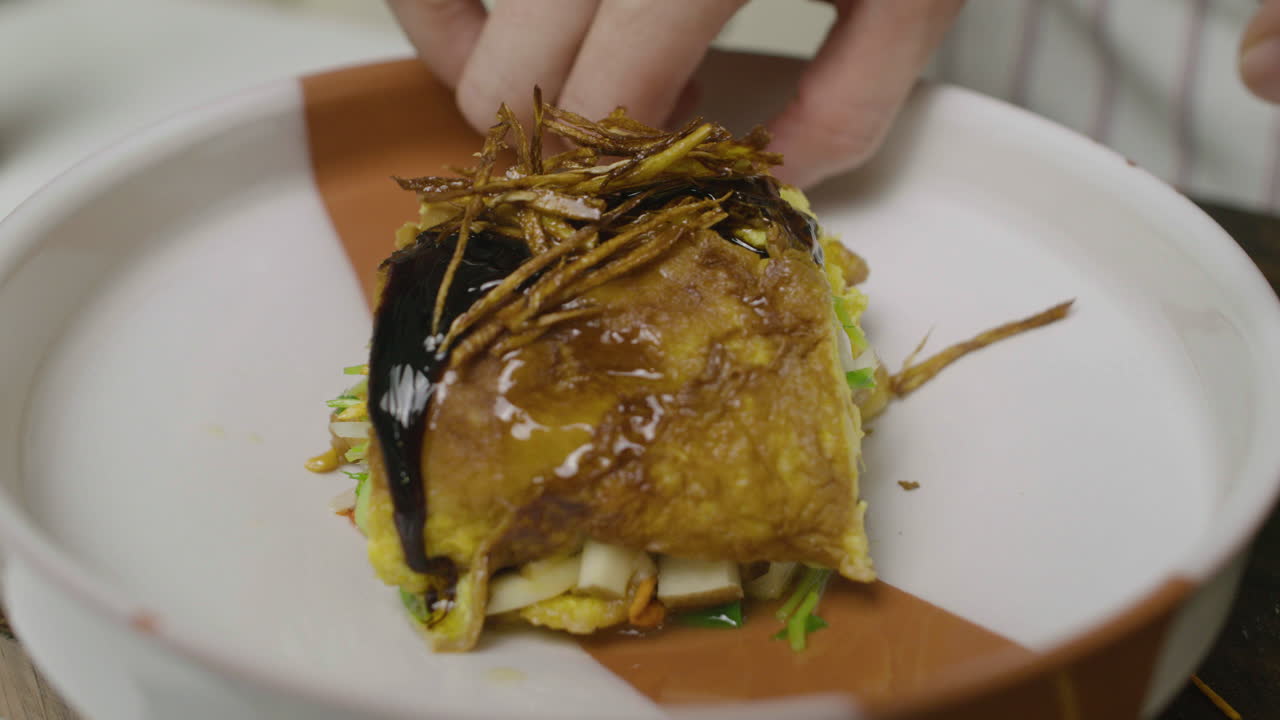 Decorating egg and abalone seafood dish with greens on top