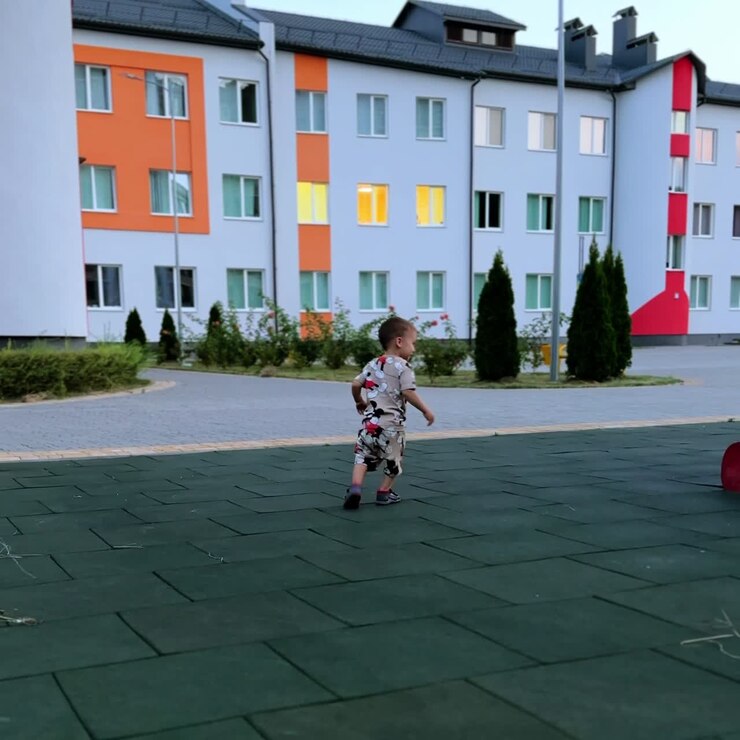 Criança caucasiana sorridente vestindo um terno com o Mickey Mouse em pé ao ar livre. Criança ativa e feliz corre, vira-se e sobe em um slide. Tela vertical