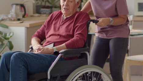 caregiver talking with elderly man in wheelchair