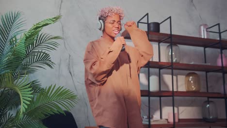 happy african woman in wireless headphones dancing and singing in remote control