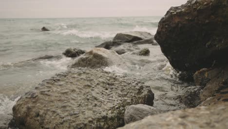 waves crashing onto rocky coastline during summer, - close up shot