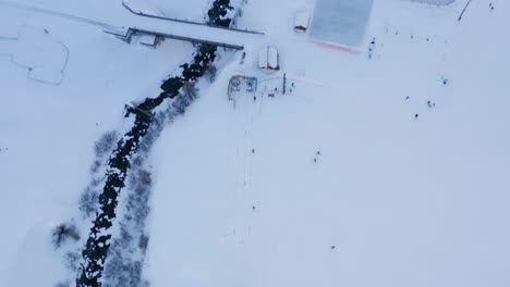 Tilt-up-from-skiers-at-resort-to-high-overview-of-beautiful-snow-covered-town-in-the-Swiss-mountains