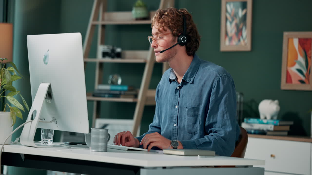 Mann arbeitet mit Headset am Computer