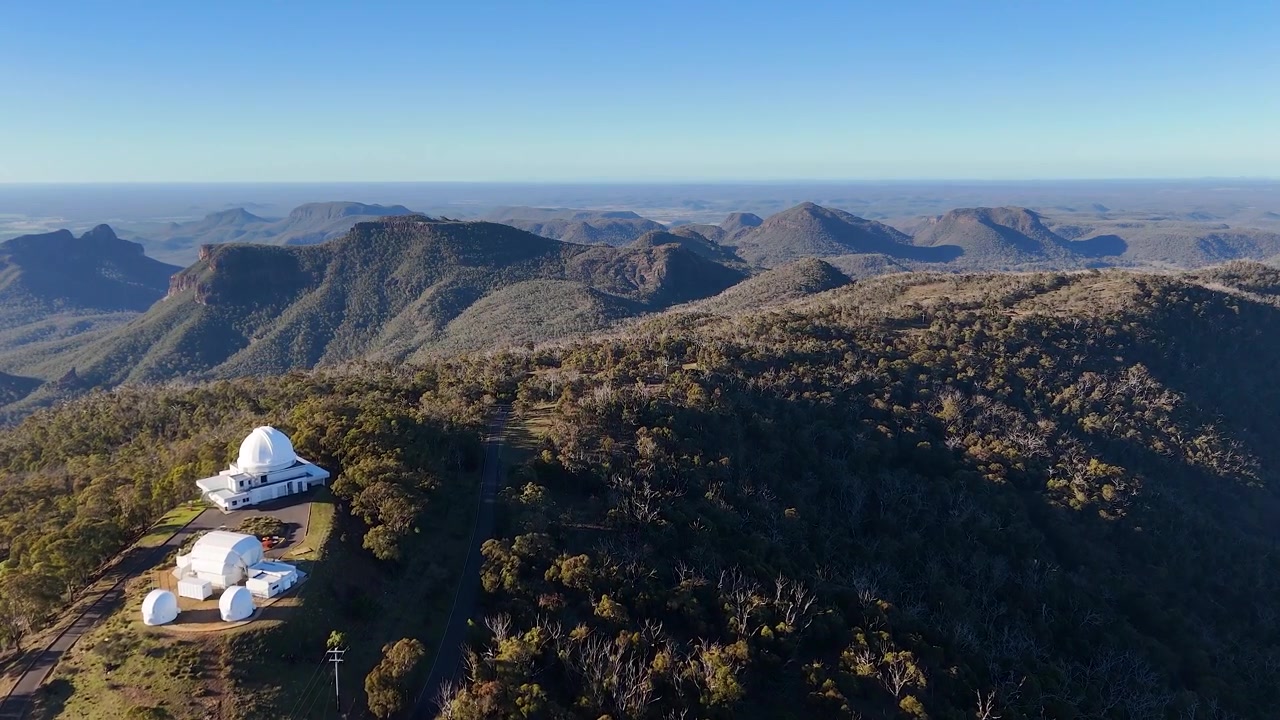 Tomada aérea ampla de cúpulas de telescópios no topo de uma cordilheira no Parque Nacional Warrumbungle, Austrália
