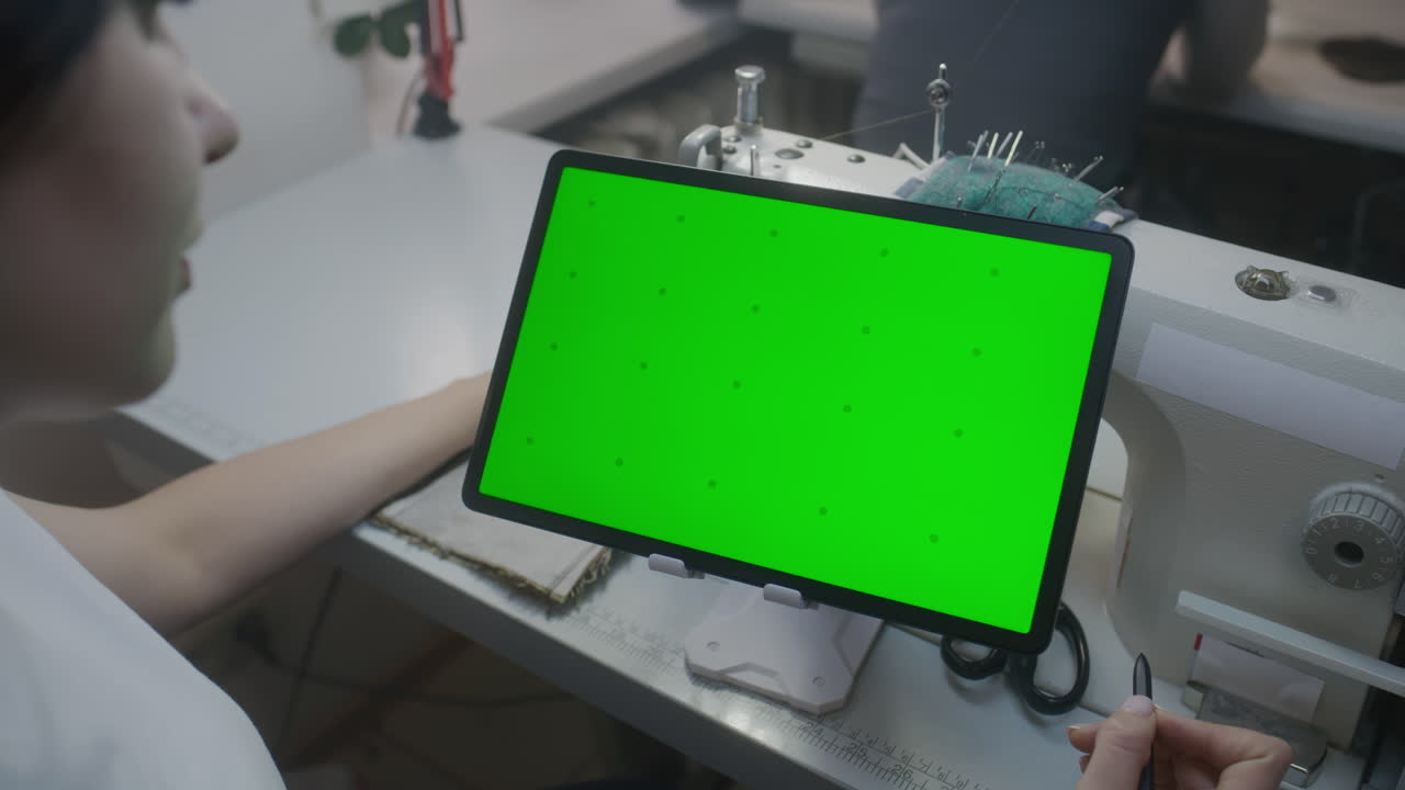Seamstress using tablet at sewing machine