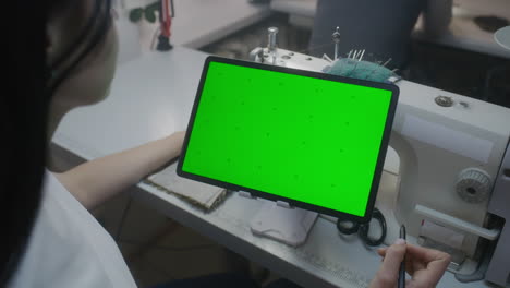 seamstress using tablet at sewing machine