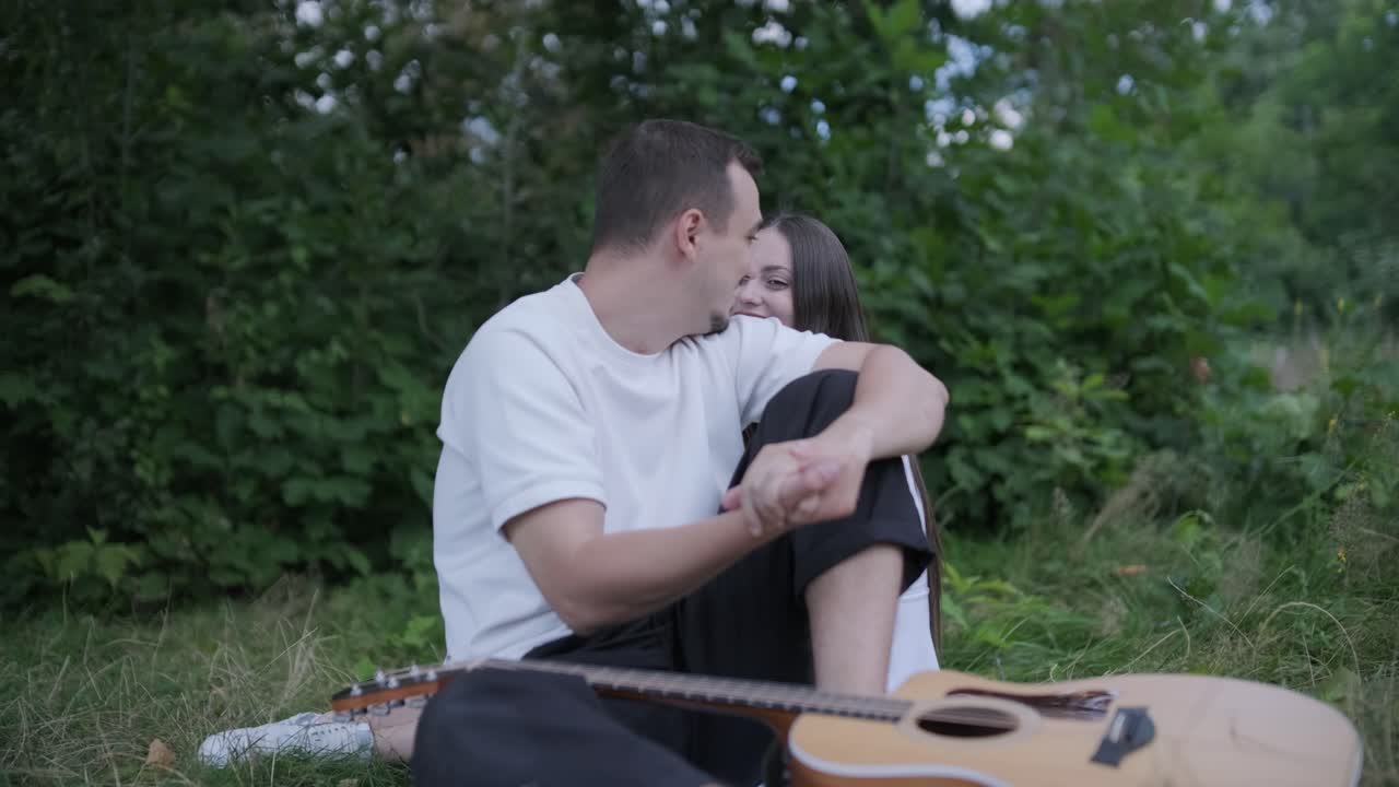 Couple sitting in park with guitar