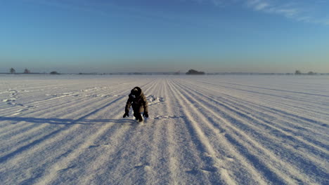 Dolly-shot-of-little-boy-walking-on-field-full-of-snow