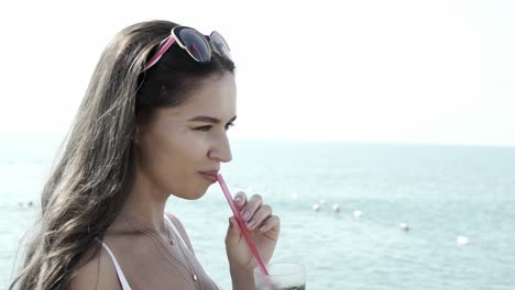 beautiful girl drinks mojito cocktail on the background of the sea