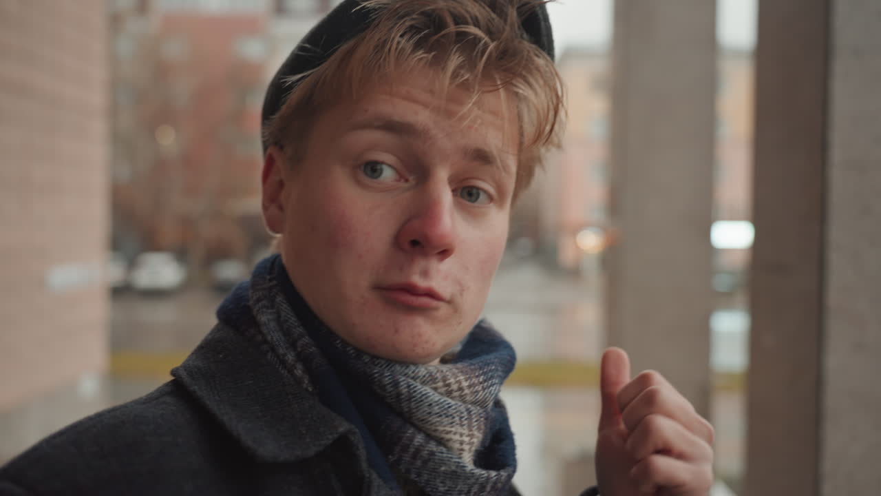 Young white creator closeup reacts to camera with playful thumb gesture scarf wet, conversational smile, influencer energy, candid urban backdrop, bokeh lights, emotional connection