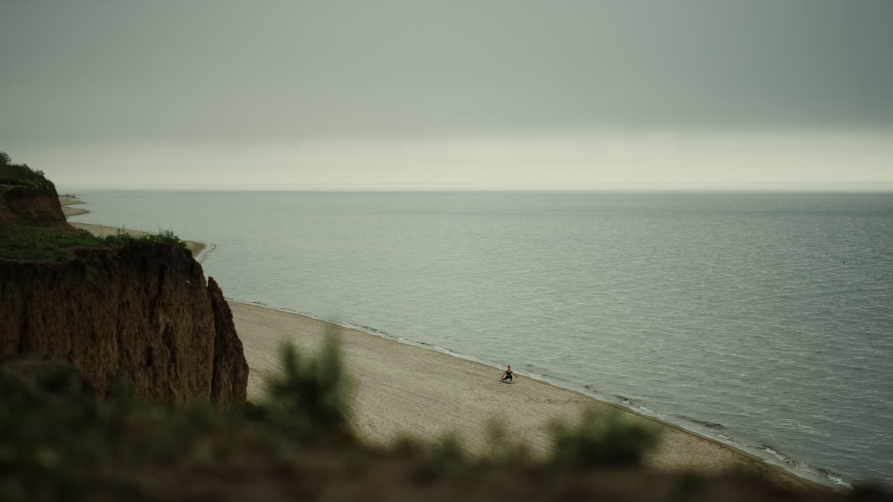 Scenic view coastline with sandy hill gloomy day. Grey cloudy sky over ocean.
