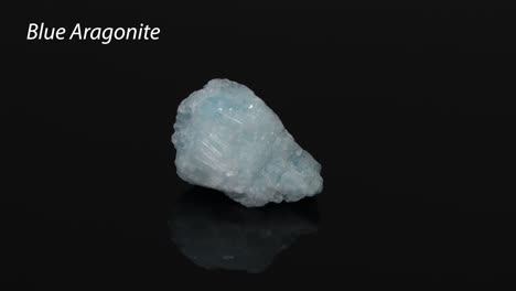 blue aragonite mineral rotating on black surface